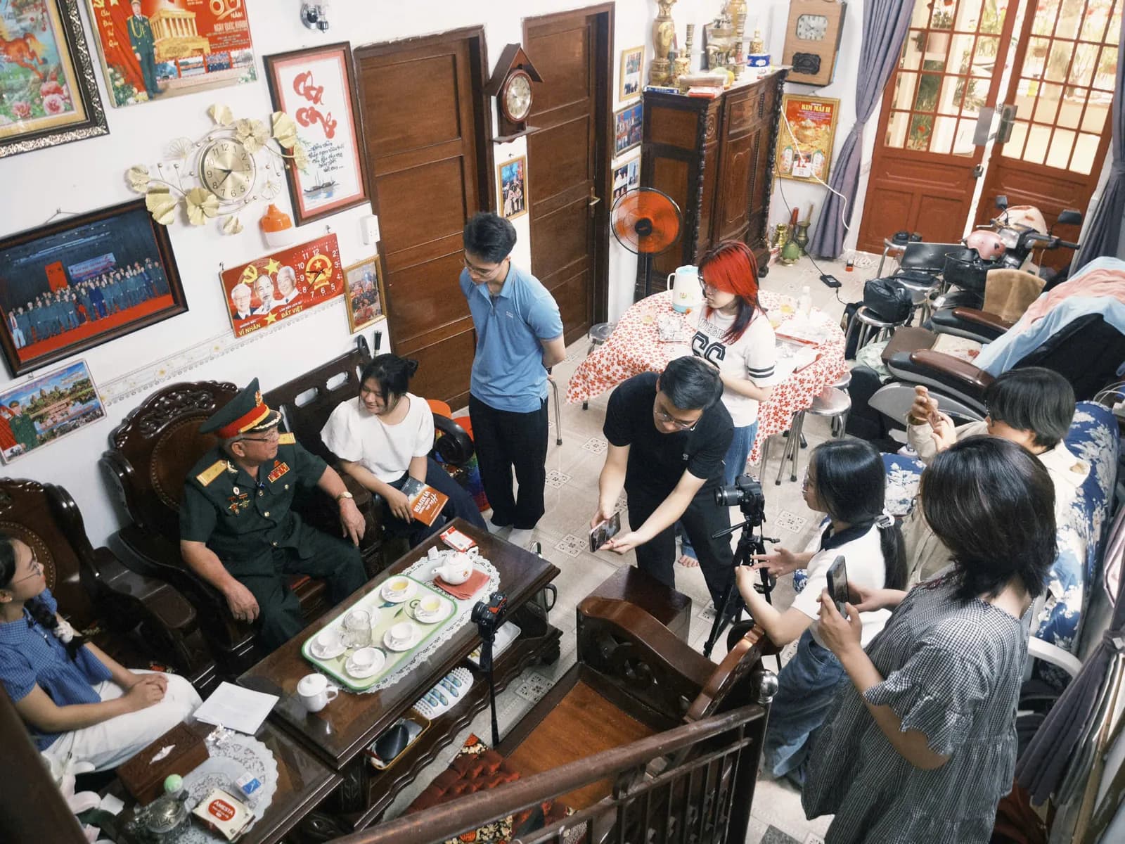Hậu trường một buổi ghi hình tại nhà: ê-kíp lắng dựng máy quay quanh bàn trà.
