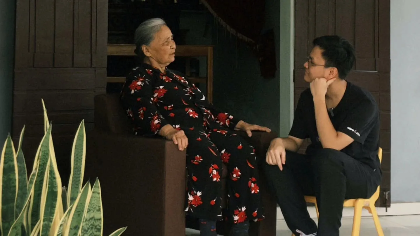 Một bà và một bạn trẻ ngồi trò chuyện với nhau trong nhà.